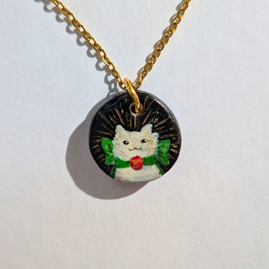 Le chat blanc au ruban vert et pendentif rouge